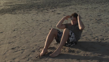 A-man-does-situps-on-a-sandy-beach