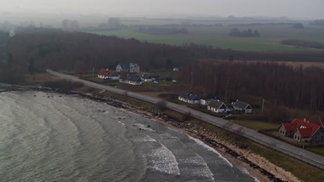 vista aérea de una playa con una calle y algunas casas familiares al borde del bosque
