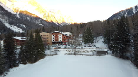 Die-Hotelgebäude-Stehen-Inmitten-Der-Unberührten-Alpenlandschaft,-Ihr-Charme-Wird-Durch-Den-Reinen-Weißen-Schnee-Noch-Verstärkt-Und-Bietet-Einen-Gemütlichen-Rückzugsort-Im-Winterwunderland-Der-Alpen