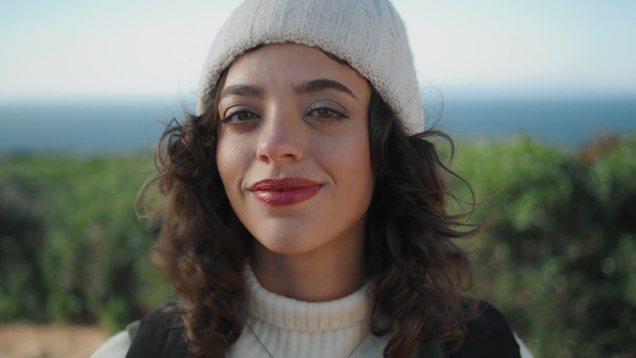 una chica alegre mirando la cámara en un día de viento en primer plano vertical. feliz joven viajero