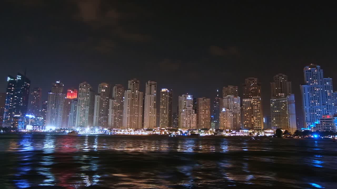 Scenic shot of the coastline at night near the beautiful buildings in Dubai, United Arab Emirates
