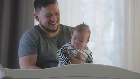 father holding a newborn baby by the window
