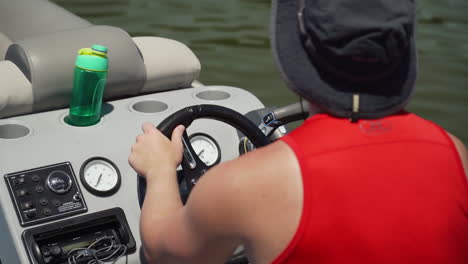 man driving pontoon boat on a lake