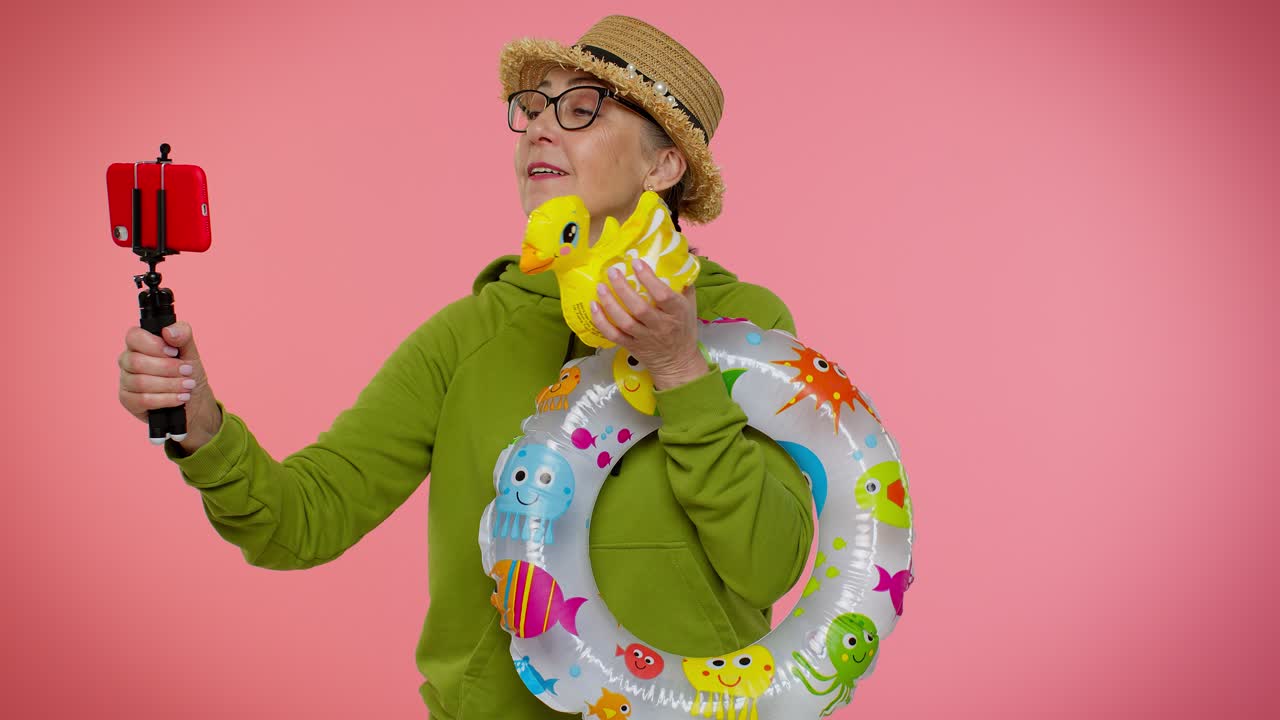 una mujer con una sudadera verde toma una selfie con un juguete de pato y un anillo inflable