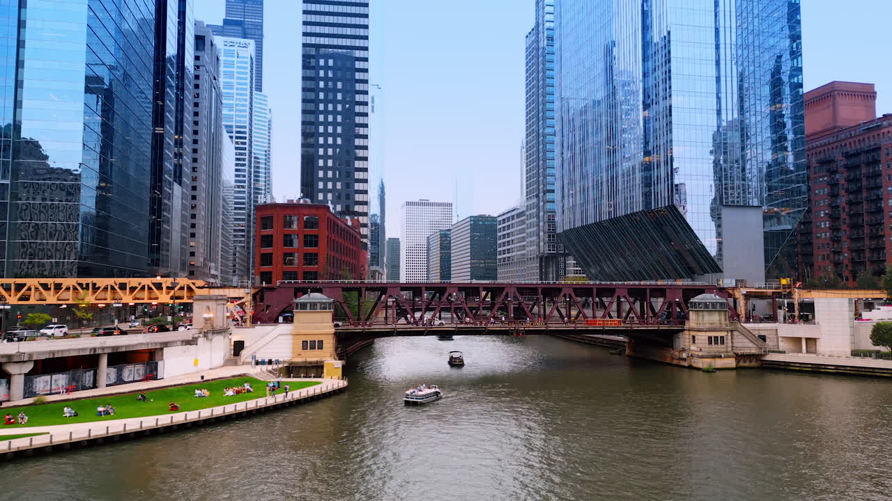 Chicago, USA, 29 June 2025: People rest at the green lawn at the waterfront of the Chicago River. Low angle view at the high-rises of the stunning city