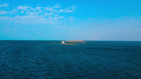 An-aerial-view-of-el-biben-island-with-a-pool-and-hosting-houses-sits-in-the-middle-of-the-ocean-with-palm-trees-on-it,-surrounded-by-water-creating-a-beautiful-atmosphere