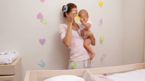 madre sosteniendo a su hija y jugando con el móvil