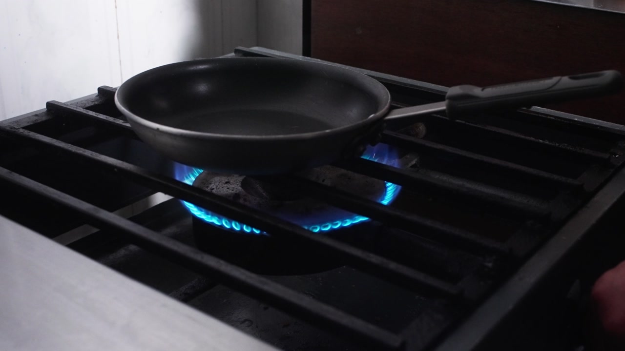 SLOW MOTION CLOSE UP SHOT OF A CHEF TURING ON A BURNER AT A KITCHEN