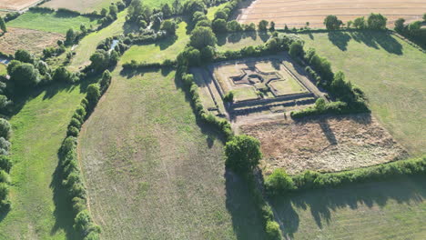 forward arc aerial of large historical ruins building surrounded by fields