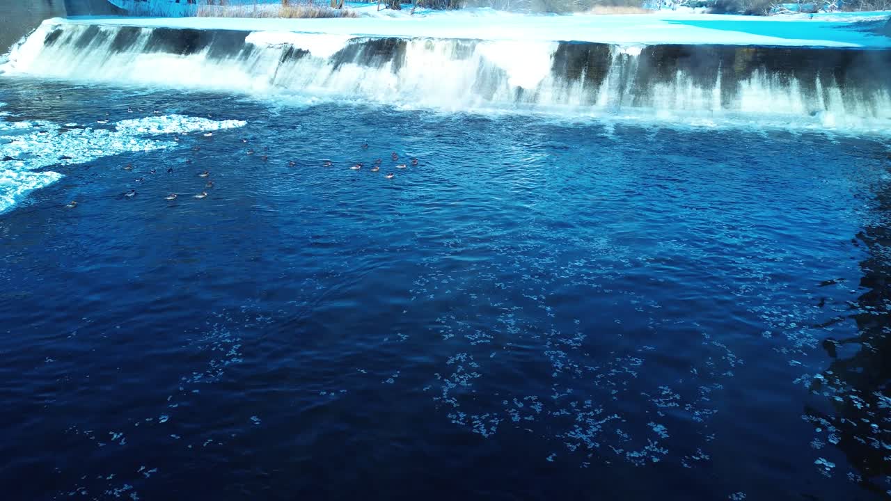 Fiume ghiacciato e diga di cemento, vista aerea con angolazione bassa.