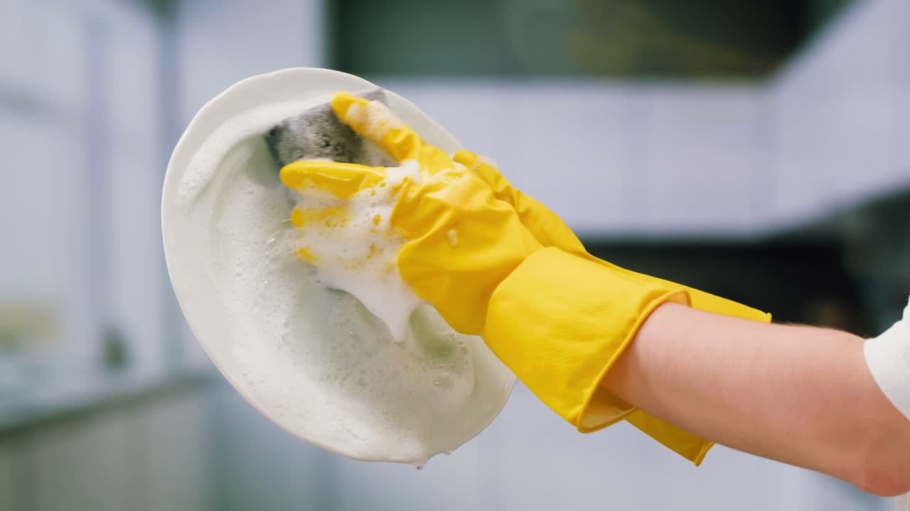 Person in Yellow Gloves Washing a Plate with Soap Suds