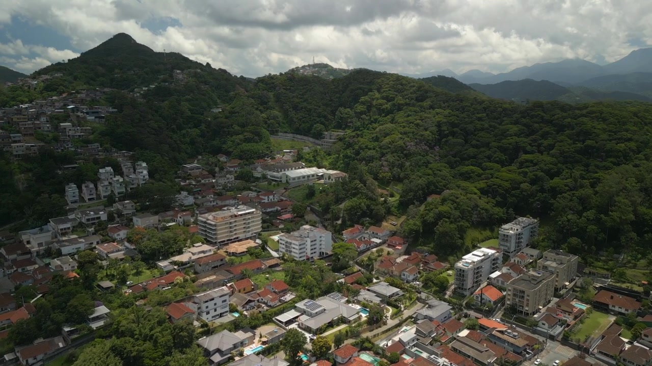 Periferia residenziale di Petrópolis che si avvicina alla fitta giungla naturale lungo i confini della città sotto un cielo parzialmente nuvoloso. Ripresa aerea registrata in 4K a 25 fps.