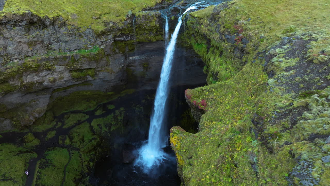 vista aérea de la cascada de kvernufoss, una cascada que fluye a través de acantilados cubiertos de musgo en islandia
