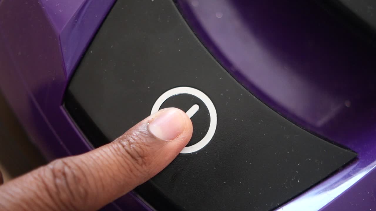 보라색 진공청소기의 손가락으로 전원 버튼을 누르면