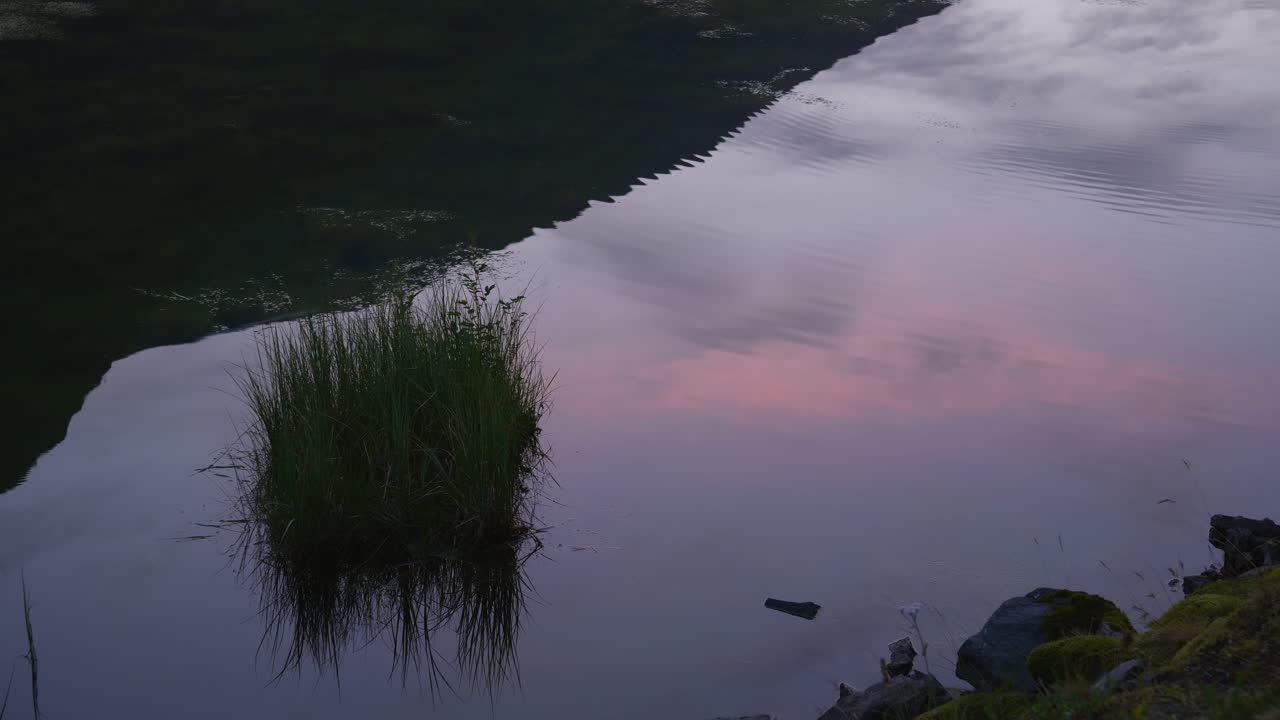 Water moves slowly with sunset reflecting in the water in Norway
