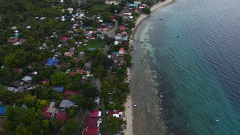 Drones-Aéreos-Vuelan-Sobre-La-Orilla-De-La-Playa-Y-El-Pueblo-En-El-Verde-Mar-Tropical-De-Filipinas-De-La-Isla-De-Cebú,-Oslob