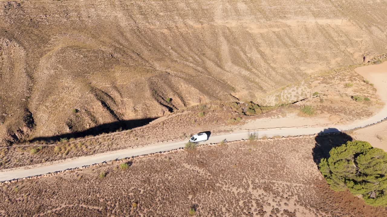 Vista aerea di un camper che guida su strada sterrata attraverso un paesaggio arido