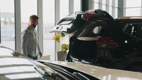 hombre mirando un suv en la sala de exposiciones de automóviles