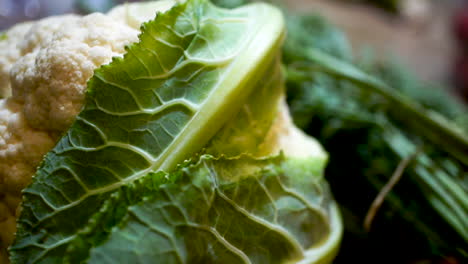 pan of whole cauliflower head with green leaves, soft focus background