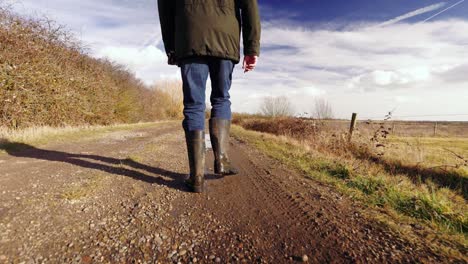 Slow-motion-of-man-walking-through-muddy-puddles-in-the-UK,-not-showing-full-person-in-the-shot,-only-3-4-of-person