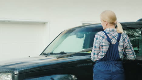 a woman washing my car in the backyard of her house on the background of the doors to the garage