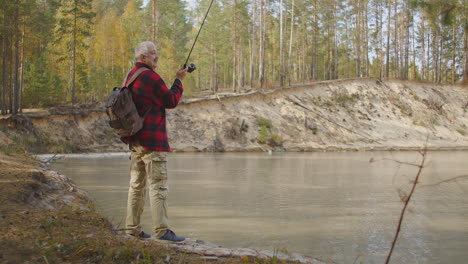 fishing on shore of reservoir man is casting fishing rod in water rest and travel in nature solitary rest at weekend