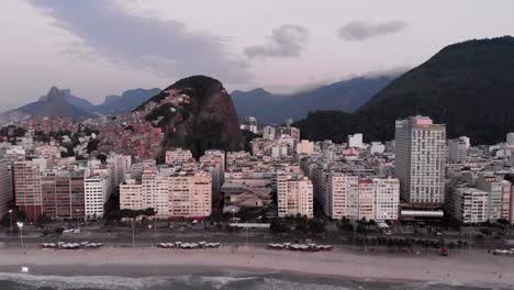 Backward-aerial-movement-showing-Copacabana-neighbourhood-in-Rio-de-Janeiro-early-in-the-morning-revealing-the-beach-and-boulevard-in-the-foreground-and-city-skyline-in-the-background