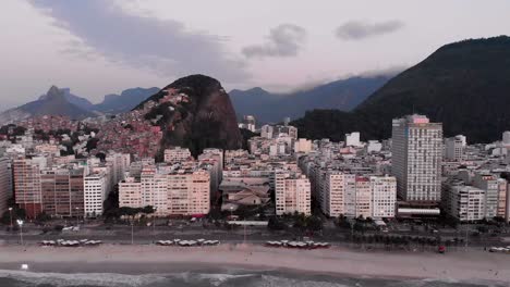 movimiento aéreo hacia atrás que muestra el barrio de copacabana en río de janeiro temprano en la mañana revelando la playa y el bulevar en primer plano y el horizonte de la ciudad en el fondo