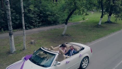 brunette bride kisses groom in convertible against park