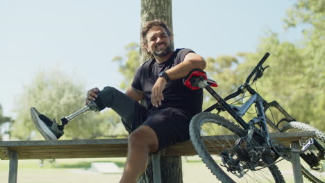 Happy-man-with-disability-sitting-on-bench-with-bionic-leg-on-it