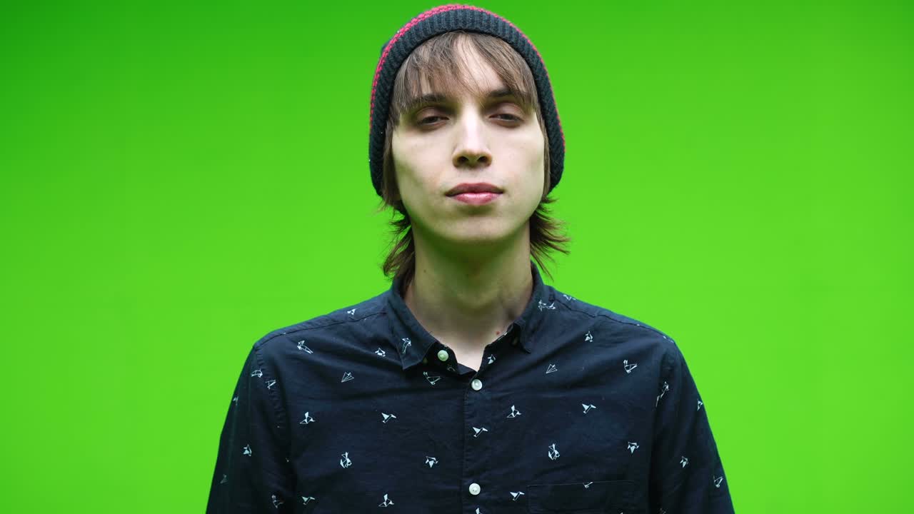 젊은이가 제거 가능한 크로마 키 배경에 머리를 흔들며 동의 상징을 하고 있습니다.