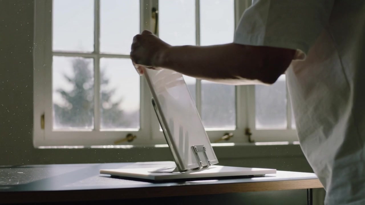 Reaching right, person in pale shirt lifting frosted panel at window, securing hinges