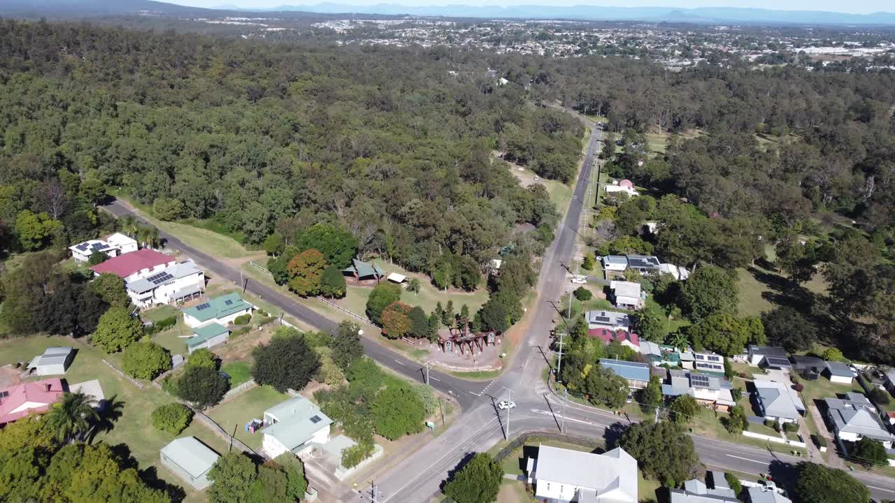4K aerial video of an intersection in an Australian town with a green bushland in the background