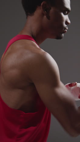 vertical video close up of male boxer with hands wrapped in protective bandages sparring before boxing match or training session