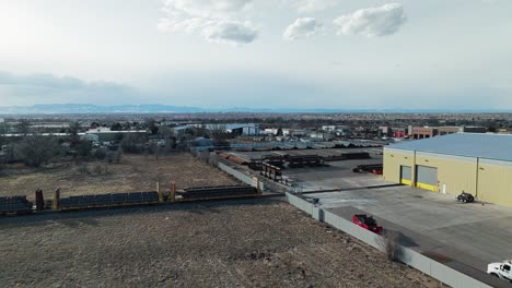 Panoramic-aerial-pullback-over-railroad-line-entering-warehouse-for-steel-beam-transport