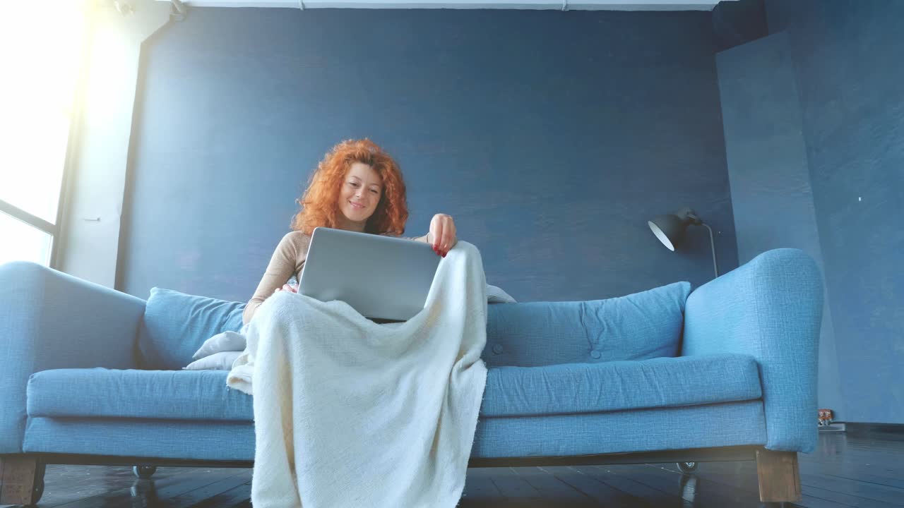 mujer relajándose en el sofá con una computadora portátil