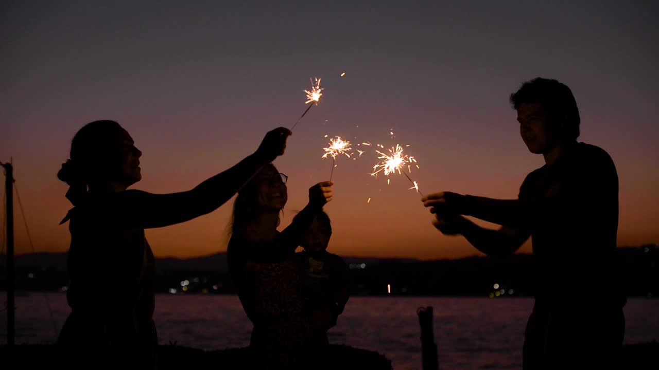 Group of friends having a party playing with bengal lights at dusk