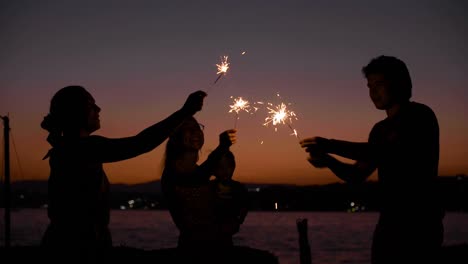 group of friends having a party playing with bengal lights at dusk