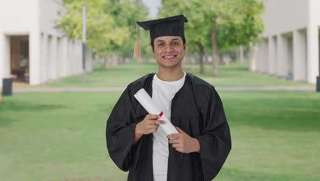 feliz estudiante universitario indio de pie con un título