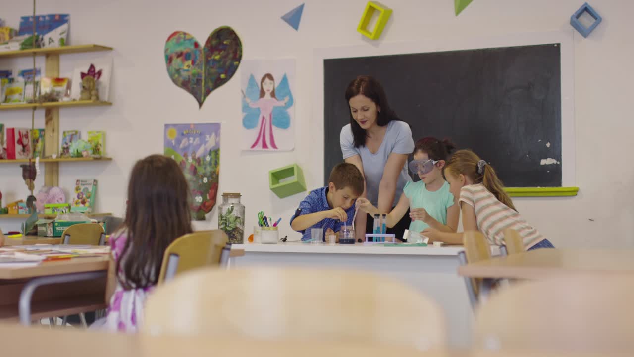 Elementary School Science Classroom: Enthusiastic Teacher Explains Chemistry to Diverse Group of Children, Little Boy Mixes Chemicals in Beakers. Children Learn with Interest