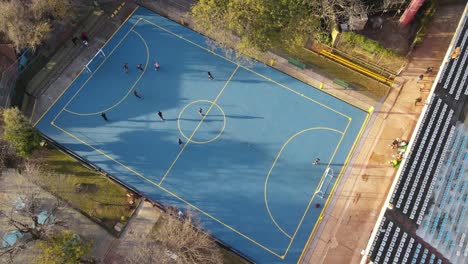 Aerial-top-down-showing-children-playing-hobby-soccer-on-blue-amateur-soccer-court-in-Buenos-Aires