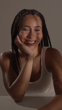 studio beauty shot of young woman with long braided hair sitting at table 4