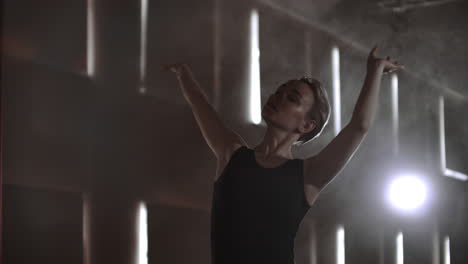 close-up of ballet dancer as she practices exercises on dark stage or studio. ballerina shows classic ballet pas. slow motion. flare gimbal shot.