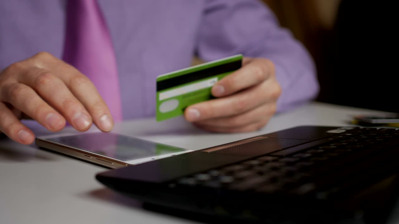 un hombre de negocios con una camisa púrpura y corbata está haciendo un pago a la banca por internet. compras en línea con tarjeta de crédito en el teléfono inteligente.