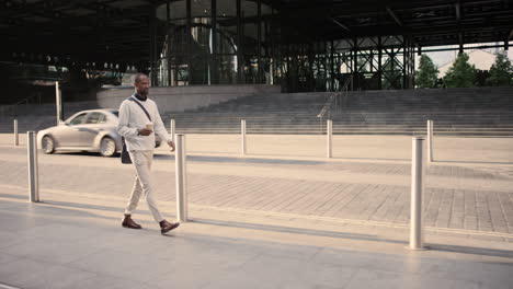 african american businessman walking through city using smart phone