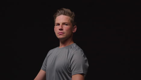 portrait of serious male athlete wearing fitness clothing training warming up and preparing psychologically for sports event against black studio background 1