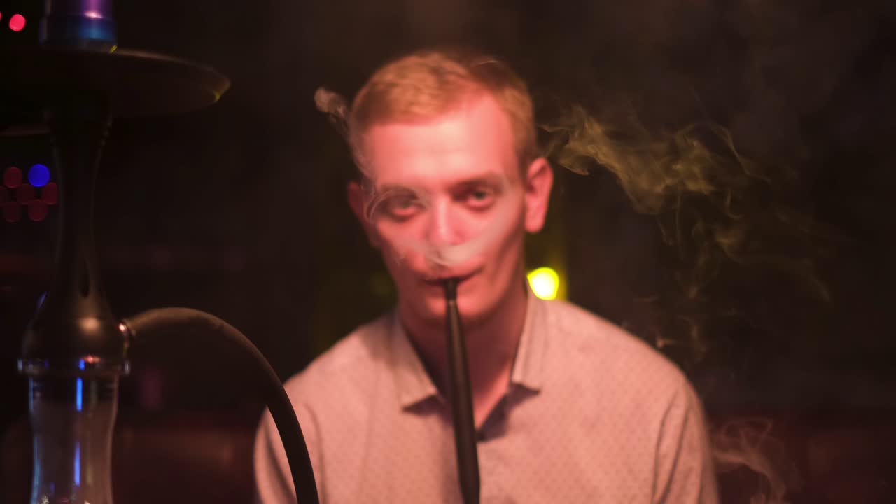 hombre fumando narguile en un club nocturno