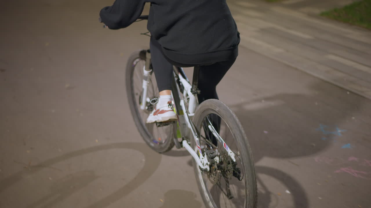 CloseUp Rear Wheel Cycling On Wet Asphalt, Athlete Pushing Pedals In Evening, Splashed Puddles, Reflective Paint, Sneaker, Motion Blur, Urban Commuter Training, Tight Framing, Dynamic Angle