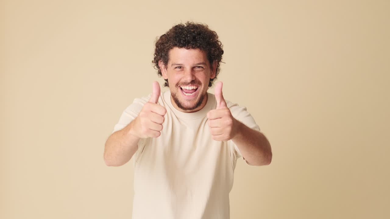 Uomo allegro che fa il doppio pollice in su su sfondo beige