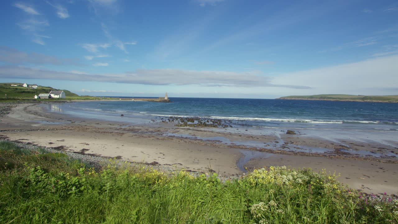 wide shot of port Logan with harbour in background and grass and in foreground